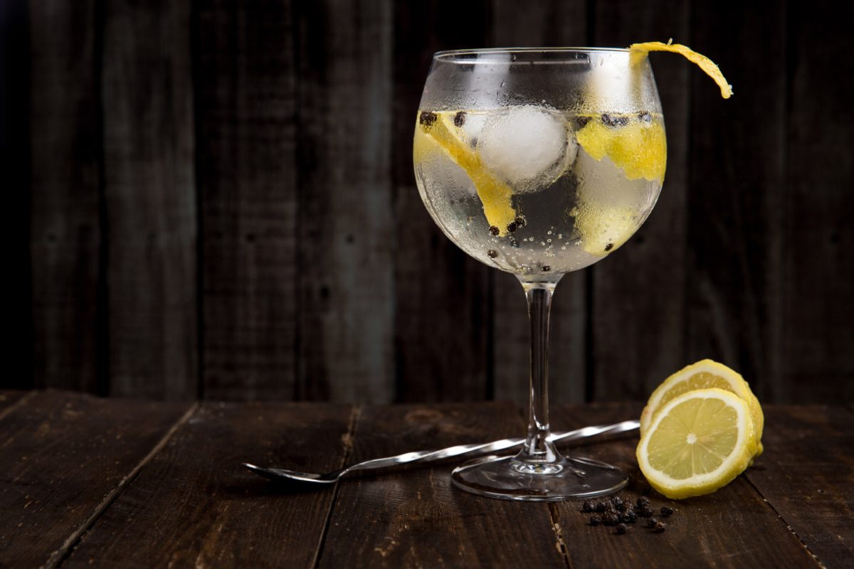 Gin cocktail sitting on a dark desk with a dark background