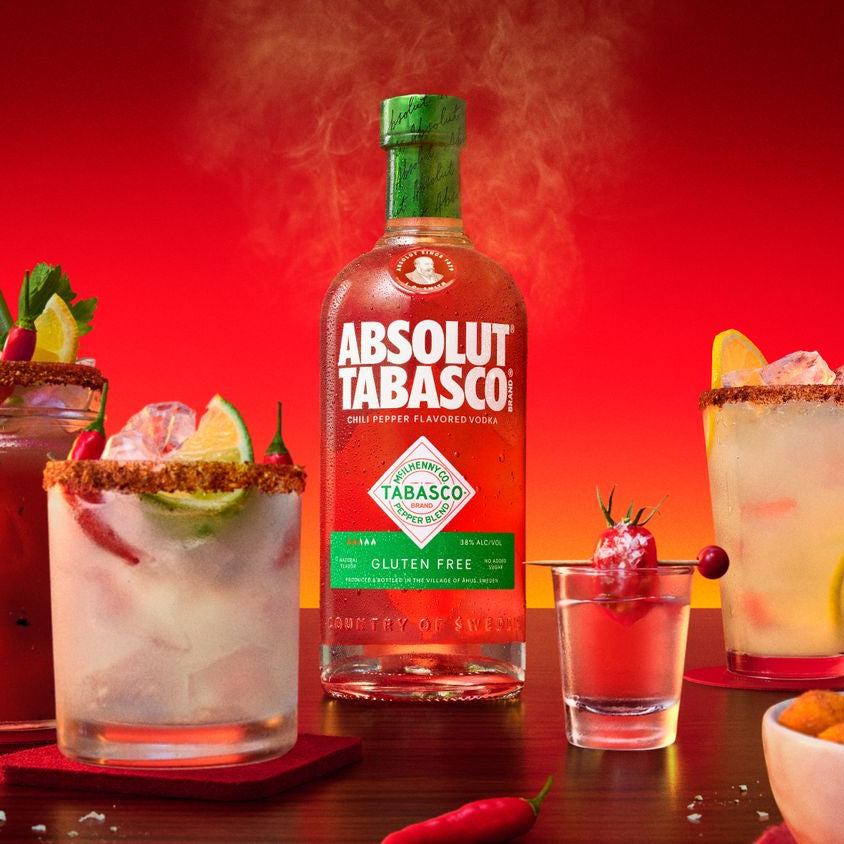 Bottle of Absolut Tabasco vodka with cocktails on a red background