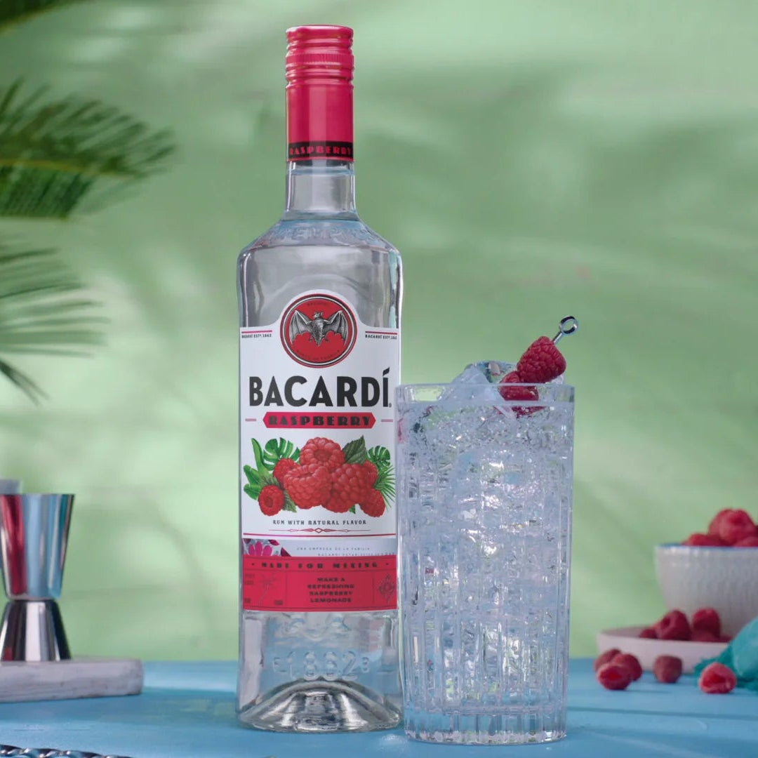 Bacardi bottle with a cocktail setup on a table with greenery in the background