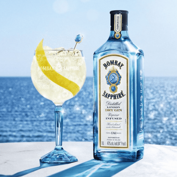 Bottle of Bombay Sapphire gin with a cocktail on a beach with ocean view