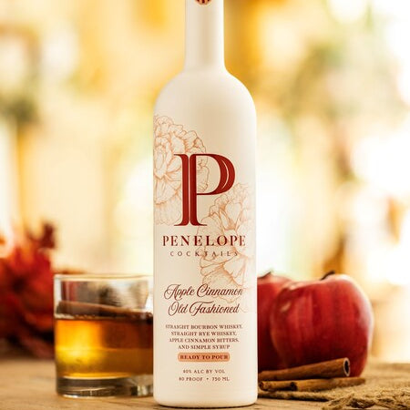 Bottle of Penelope Apple Cinnamon Old Fashioned cocktail with a blurred background