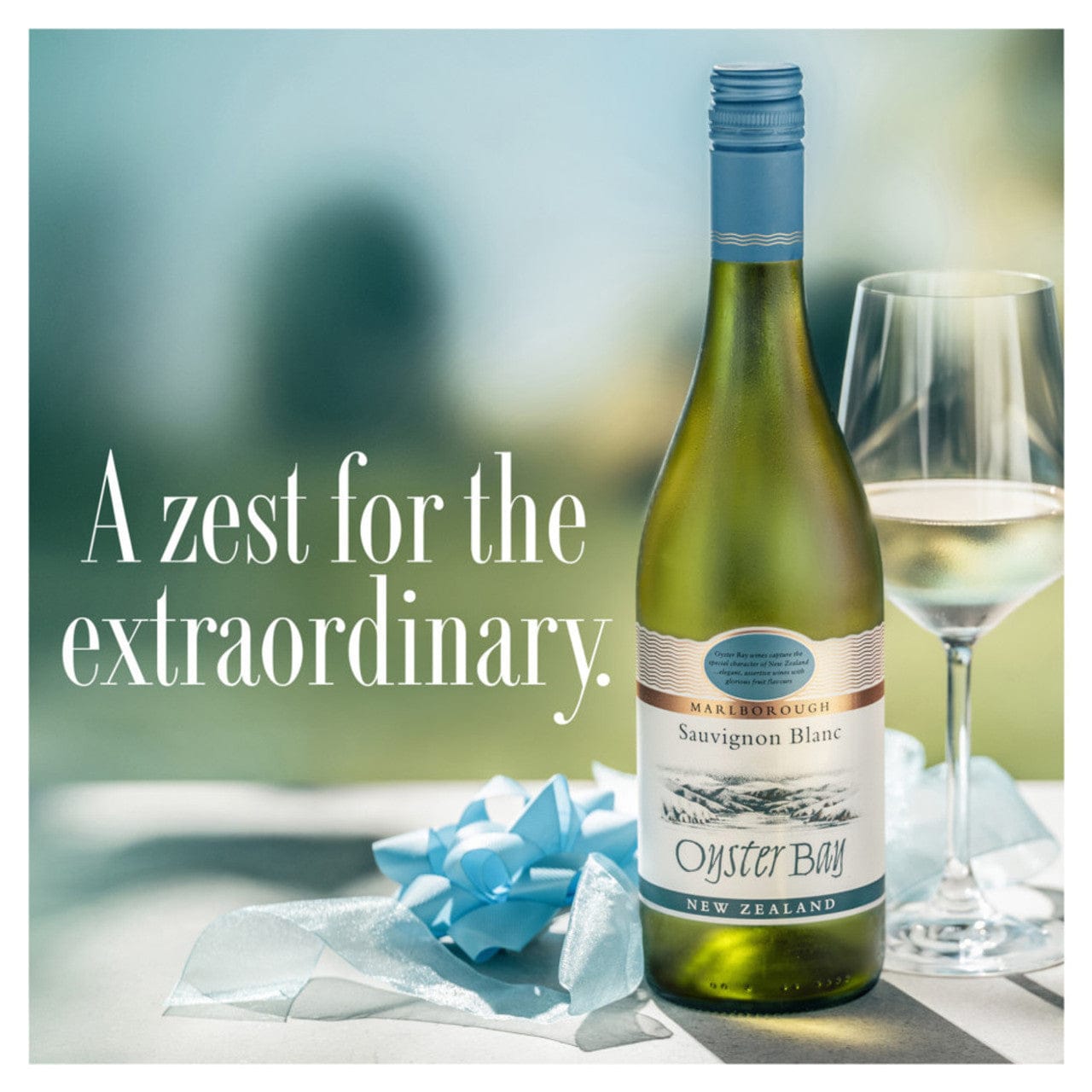 Oyster Bay Sauvignon Blanc wine bottle with a glass on a blurred outdoor background