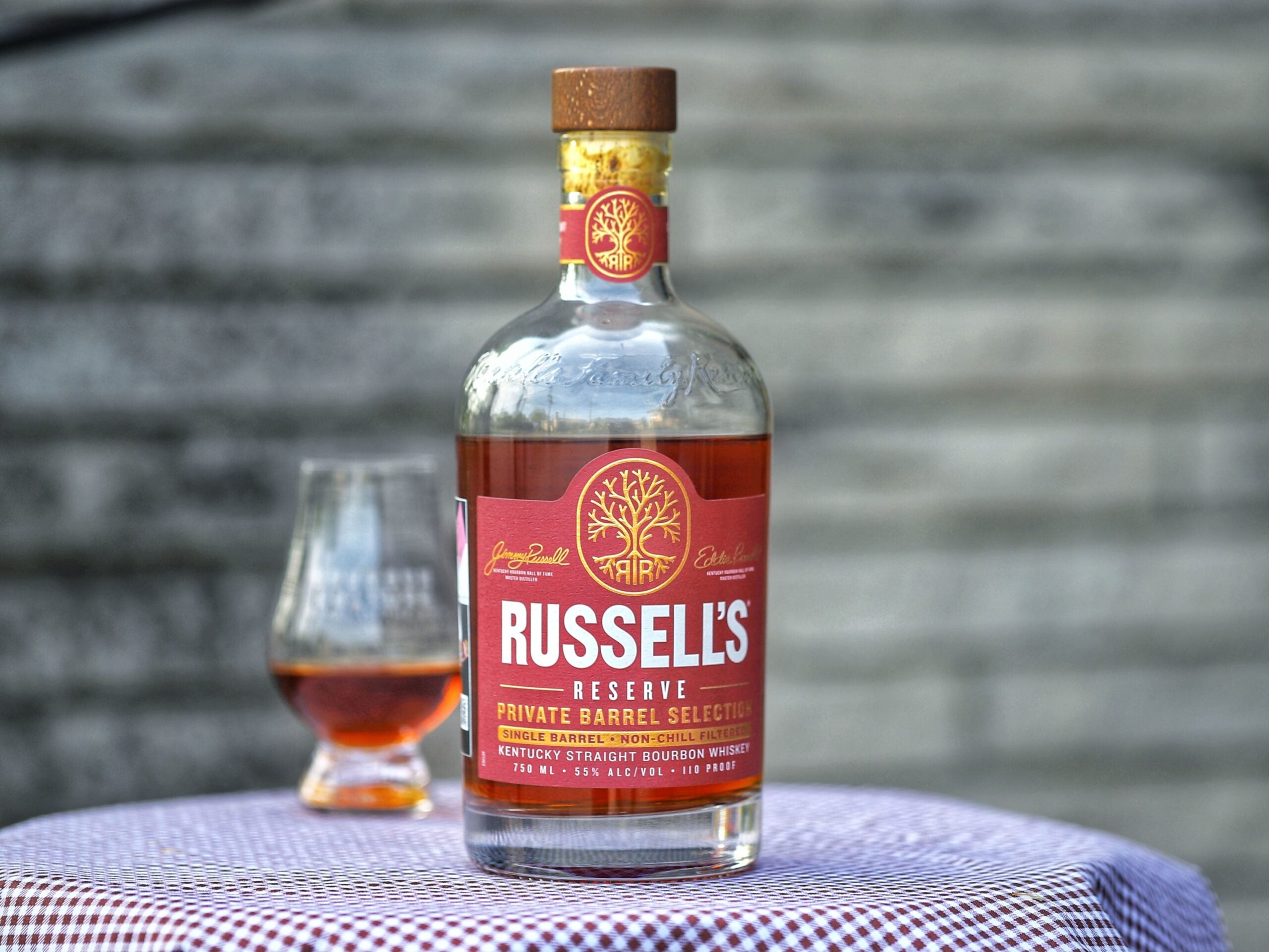 Bottle of Russell's Reserve bourbon on a checkered tablecloth with a blurred background