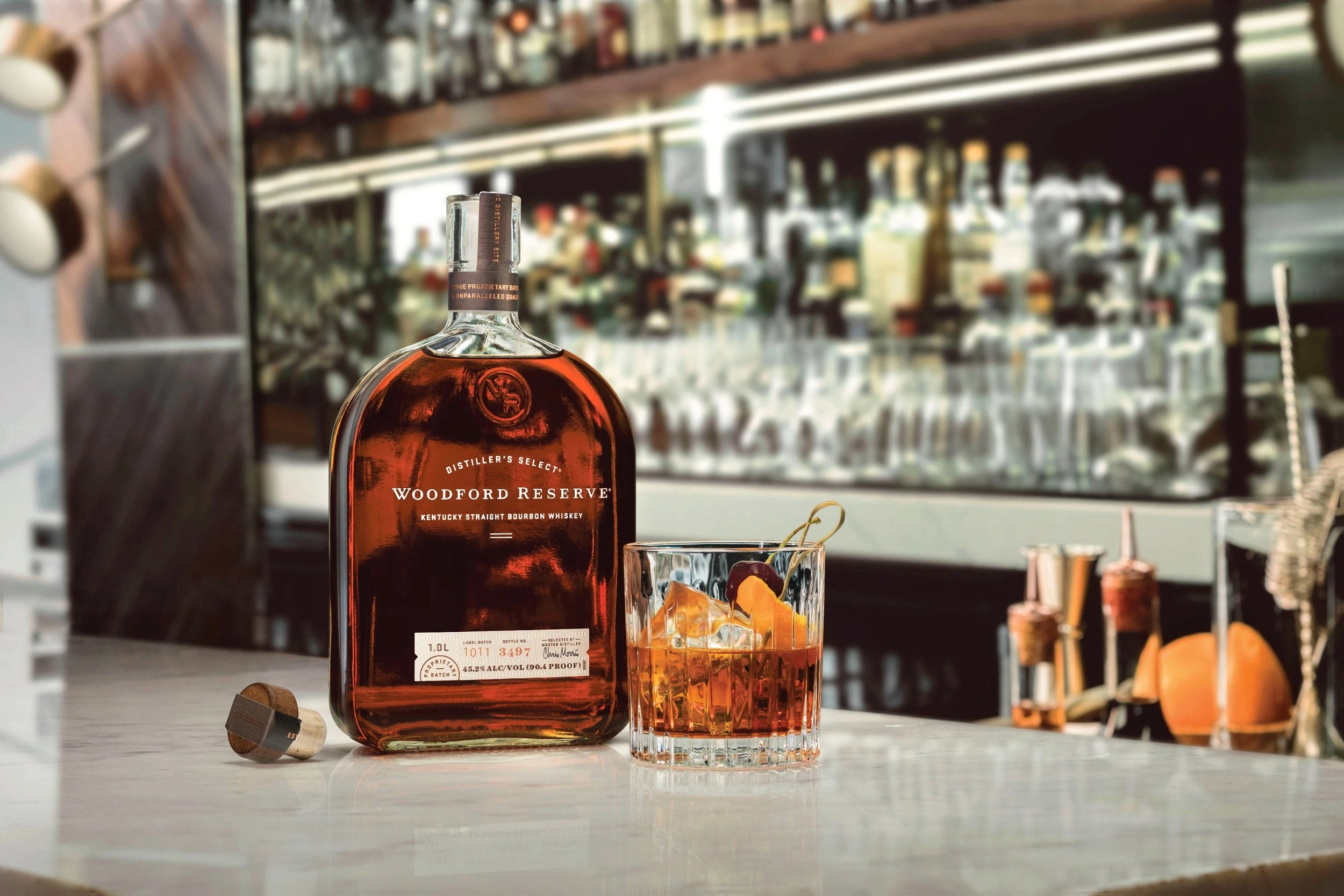 Woodford Reserve Kentucky Straight Bourbon Whiskey bottle and Old Fashioned cocktail on bar counter – premium American bourbon for classic whiskey drinks.