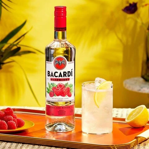 Bacardi bottle with a cocktail and fruit on a tray against a yellow background