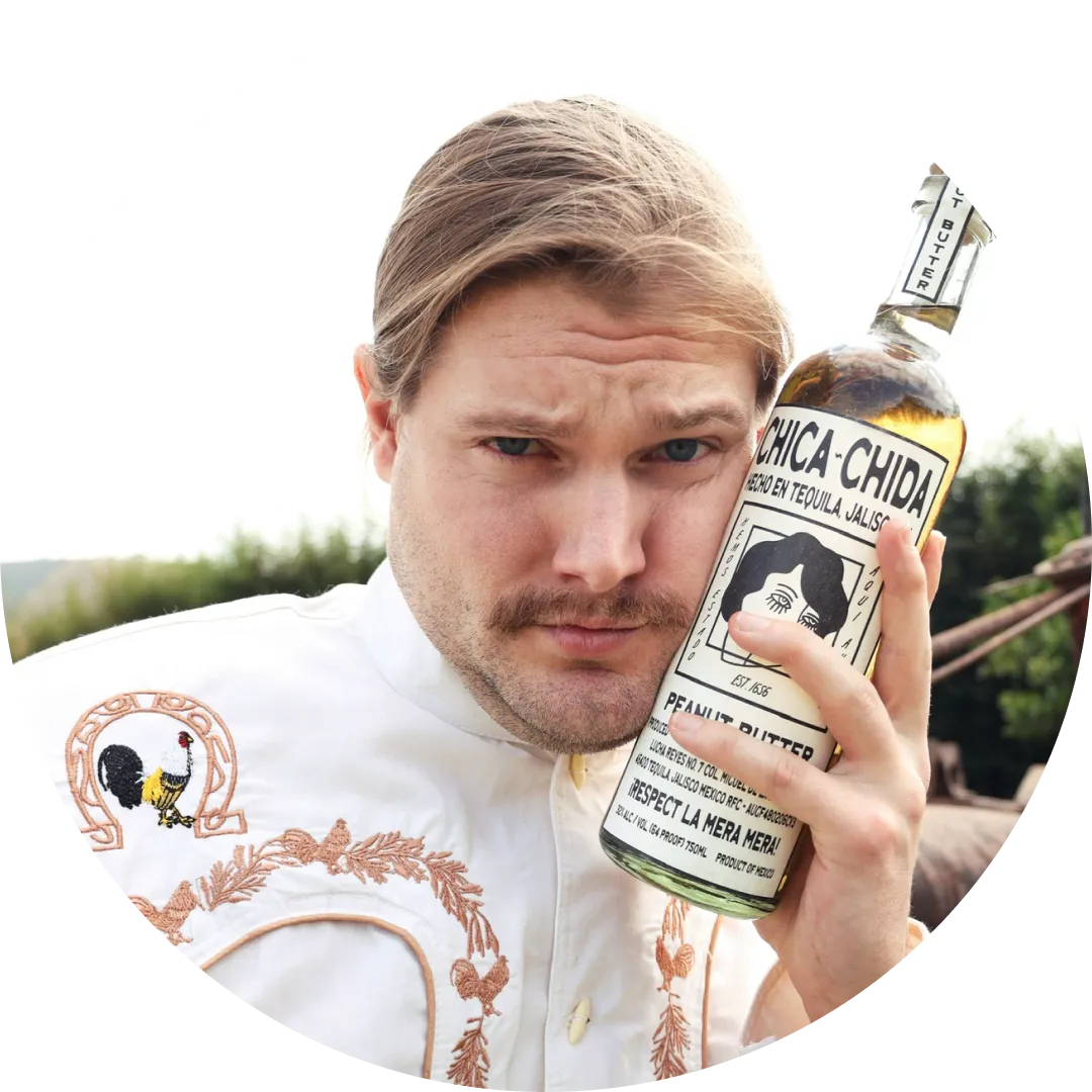 Caleb Pressley holding a bottle of Chica Chida tequila with a blurred outdoor background