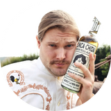 Caleb Pressley holding a bottle of Chica Chida tequila with a blurred outdoor background