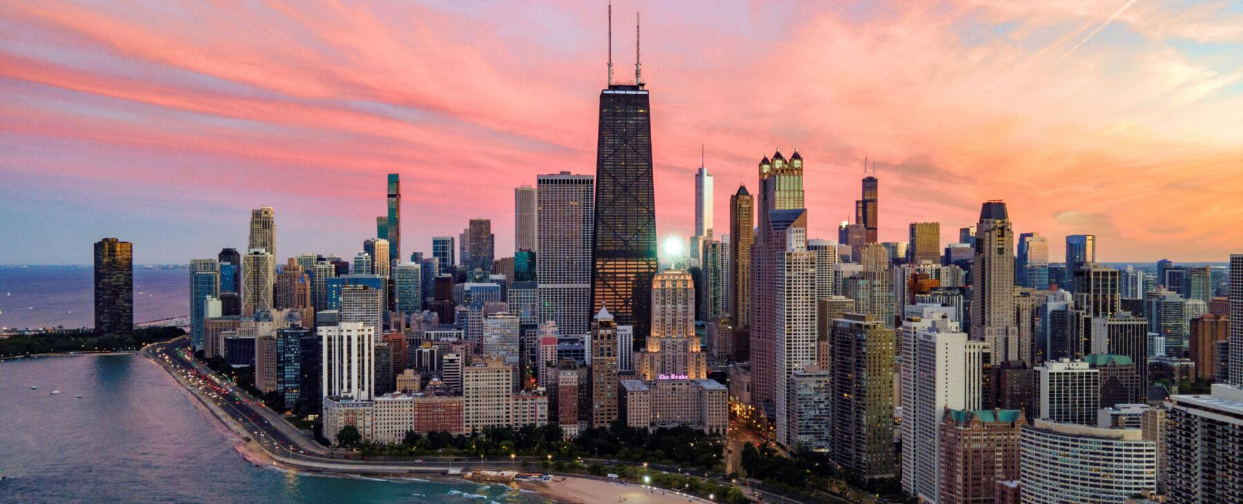 City skyline with skyscrapers and a sunset sky over water