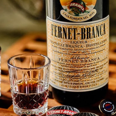 Fernet-Branca bottle with two shot glasses on a wooden surface