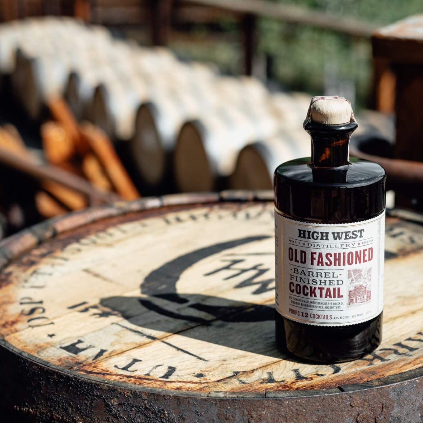 Bottle of High West Old Fashioned Barrel Aged Cocktail on a wooden barrel with rustic background