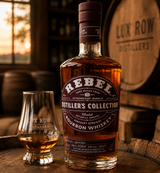 Bottle of Rebel Distiller's Collection bourbon whiskey with a glass on a wooden barrel, Lux Row Distillers background.