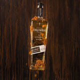 Bottle of Tromba tequila surrounded by sand on a wooden background
