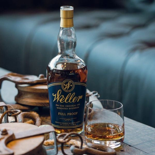 Weller whiskey bottle with a glass of whiskey on a wooden table.