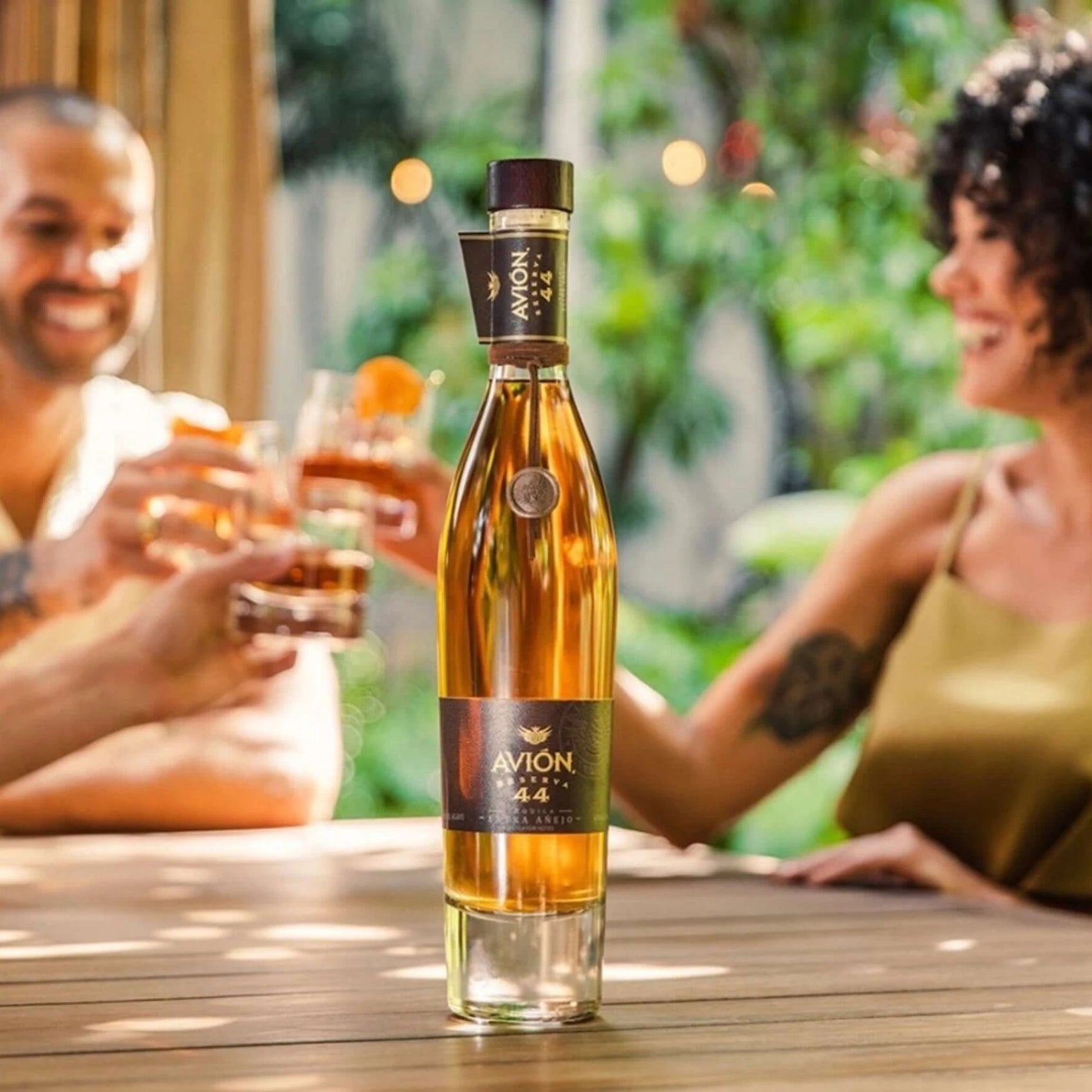 Avión 44 Reserva Extra Añejo Tequila bottle with friends toasting – luxury aged tequila lifestyle image