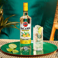 Bacardi rum bottle with a cocktail on a green tray against a blurred natural background