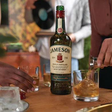 Jameson Irish Whiskey being poured into glasses at a party with friends in the background
